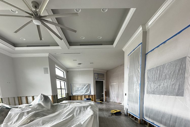 Living room with covered furnishings, plastic sheeting and exposed framing along the lower walls